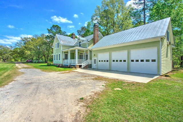 view of front of property featuring a chimney, dirt driveway, a front lawn, metal roof, and covered porch