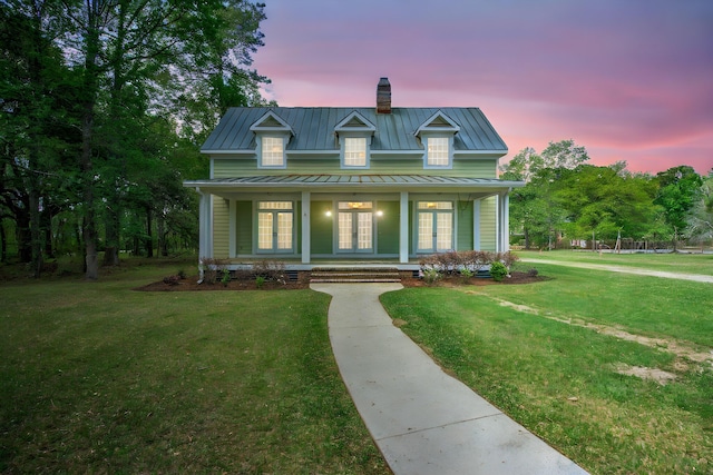 view of front of house with a standing seam roof, a chimney, metal roof, a front yard, and french doors