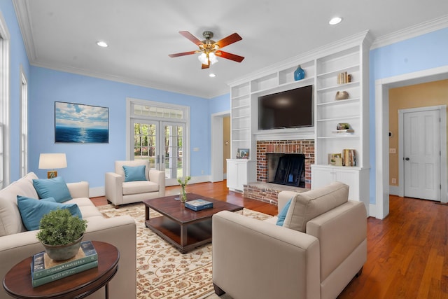 living area with ornamental molding, ceiling fan, light wood finished floors, and a fireplace