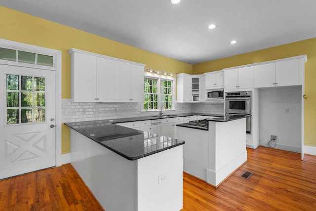 kitchen with stainless steel appliances, a peninsula, white cabinets, and visible vents