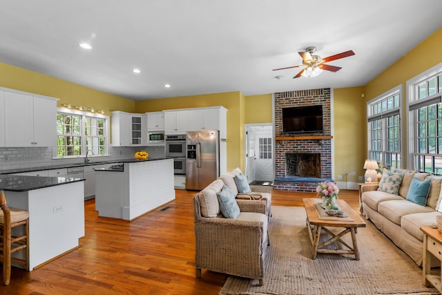 living area featuring recessed lighting, a fireplace, light wood-type flooring, and ceiling fan
