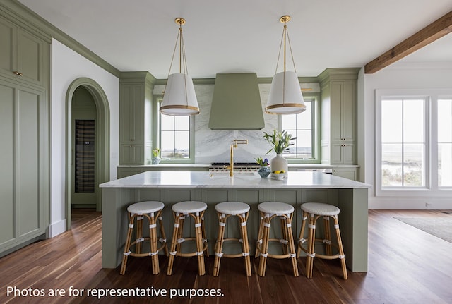 kitchen featuring hardwood / wood-style flooring, a breakfast bar area, a center island with sink, and hanging light fixtures