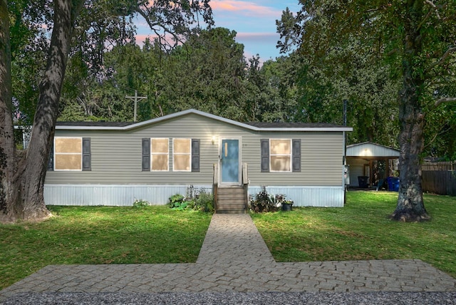 manufactured / mobile home featuring a lawn and a carport