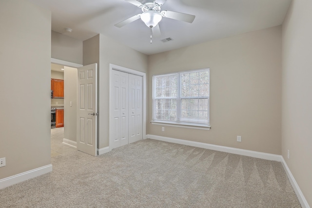 unfurnished bedroom featuring light carpet, a closet, and ceiling fan