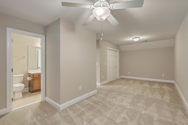 unfurnished bedroom with a closet, ceiling fan, connected bathroom, and light colored carpet