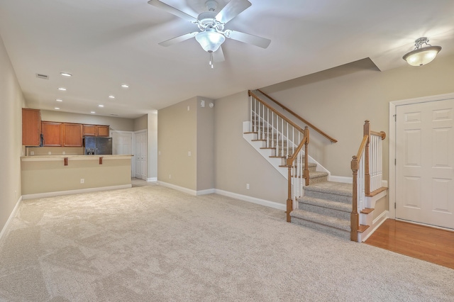 unfurnished living room featuring ceiling fan and light carpet