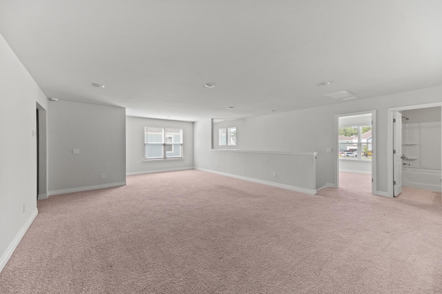 empty room with plenty of natural light, light carpet, and baseboards
