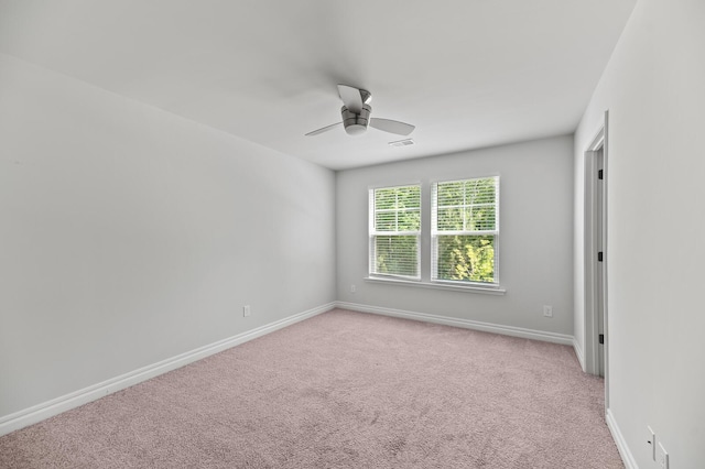 empty room featuring a ceiling fan, light colored carpet, and baseboards