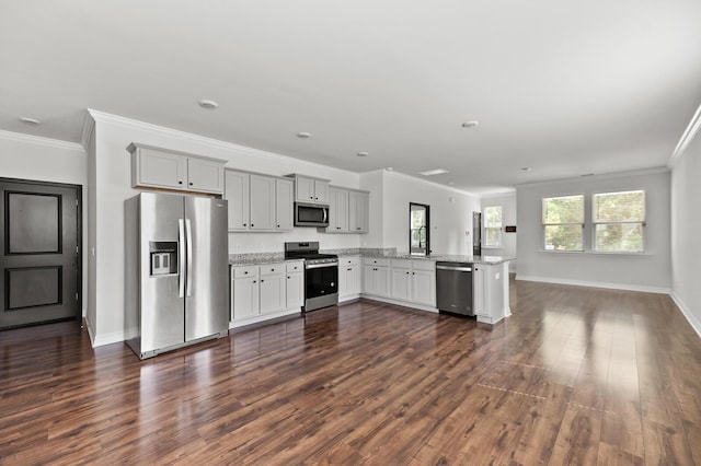 kitchen featuring stainless steel appliances, a sink, a peninsula, crown molding, and dark wood-style floors