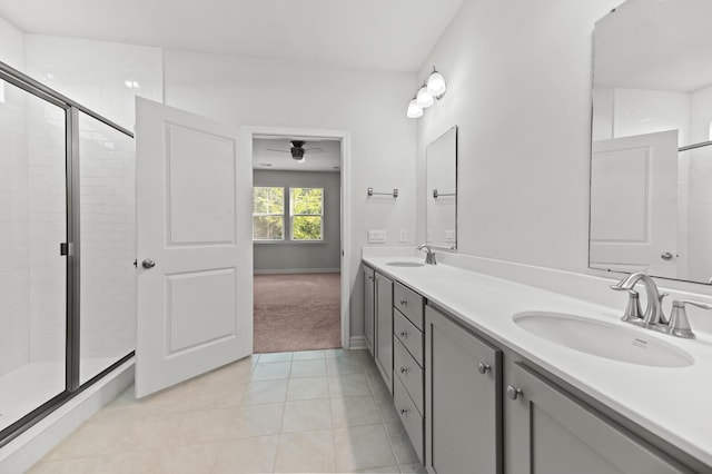 full bathroom with a ceiling fan, a shower stall, double vanity, tile patterned floors, and baseboards