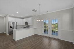 kitchen with french doors, dark hardwood / wood-style flooring, kitchen peninsula, stainless steel fridge, and hanging light fixtures