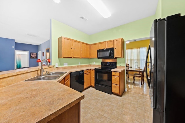 kitchen featuring visible vents, light countertops, a sink, a peninsula, and black appliances