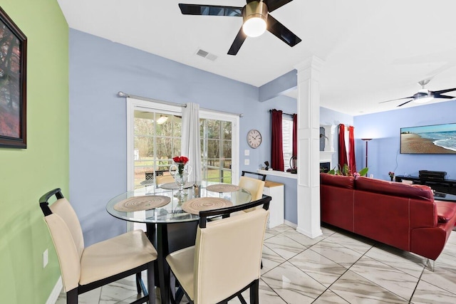 dining space featuring baseboards, a ceiling fan, visible vents, and ornate columns