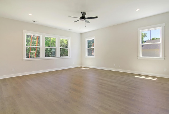 spare room featuring ceiling fan, dark wood-type flooring, and a wealth of natural light