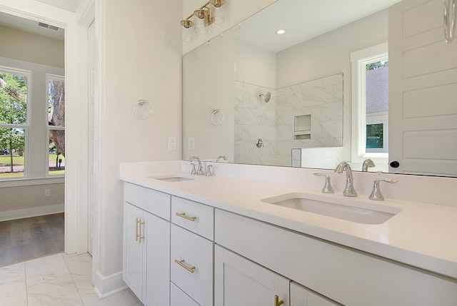 full bathroom featuring marble finish floor, baseboards, a tile shower, and a sink