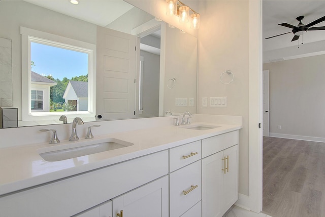 bathroom featuring double vanity, a sink, baseboards, and wood finished floors