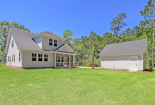 back of property with a sunroom, roof with shingles, and a yard