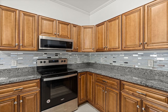 kitchen with dark stone counters, crown molding, stainless steel appliances, and backsplash