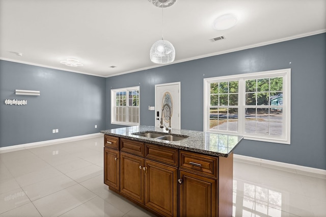 kitchen featuring pendant lighting, an island with sink, light tile patterned floors, sink, and crown molding