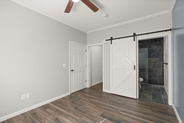 unfurnished bedroom featuring ceiling fan, connected bathroom, crown molding, a barn door, and dark hardwood / wood-style flooring