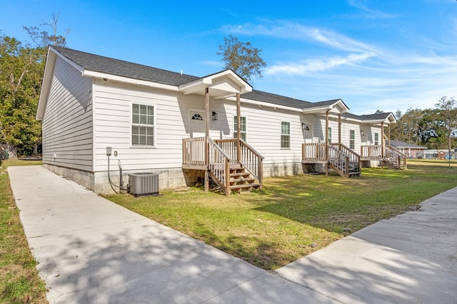 view of front of house with central AC and a front lawn