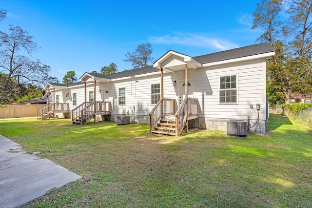 rear view of house featuring central AC unit and a yard