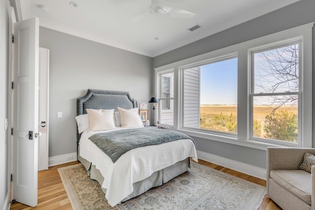 bedroom with ornamental molding, ceiling fan, and light hardwood / wood-style floors