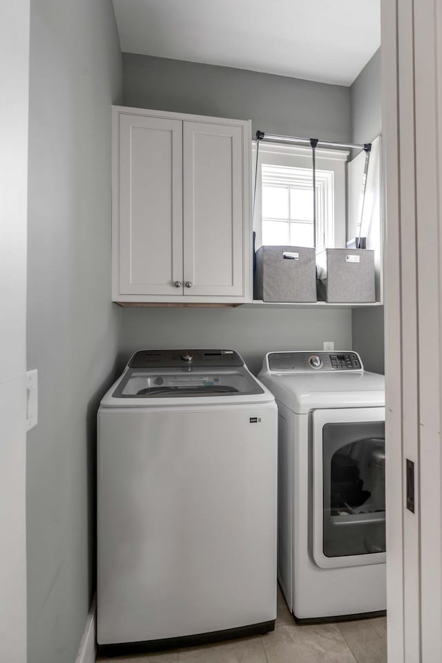 laundry area with cabinets, light tile patterned flooring, and independent washer and dryer