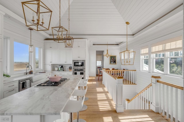 kitchen with pendant lighting, appliances with stainless steel finishes, a kitchen island, and white cabinets