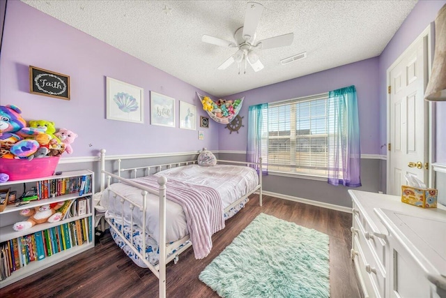 bedroom featuring visible vents, baseboards, ceiling fan, dark wood finished floors, and a textured ceiling