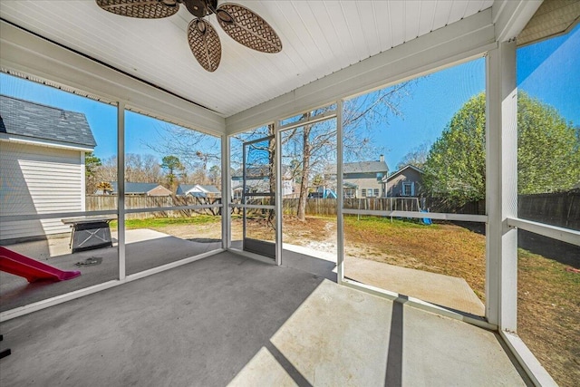 unfurnished sunroom featuring a residential view and ceiling fan