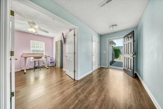 foyer featuring visible vents, a textured ceiling, baseboards, and wood finished floors