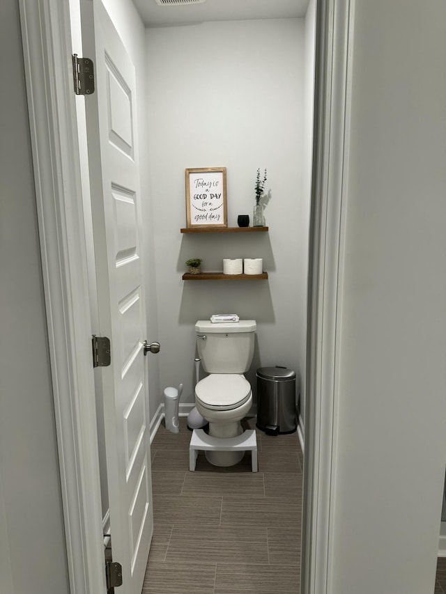 bathroom featuring toilet, baseboards, and visible vents