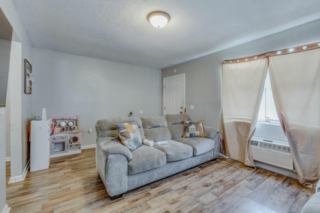 living room with cooling unit, light hardwood / wood-style flooring, and a textured ceiling