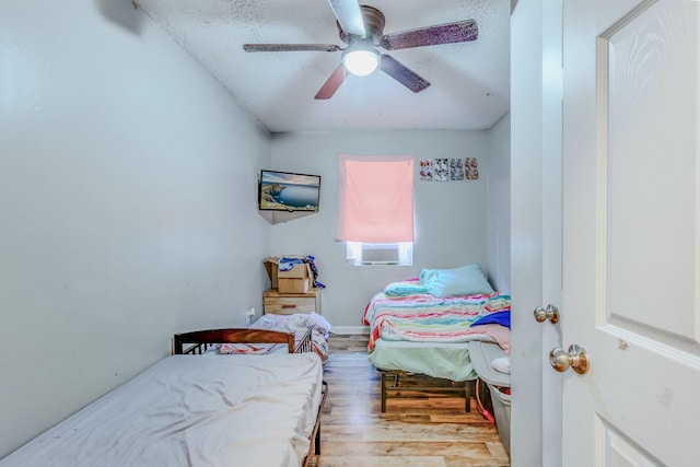 bedroom with ceiling fan, cooling unit, a textured ceiling, and light wood-type flooring