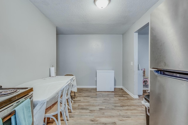 dining room featuring a textured ceiling and light wood-type flooring