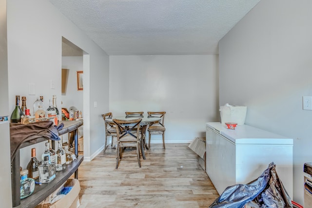 dining space with a textured ceiling and light wood-type flooring