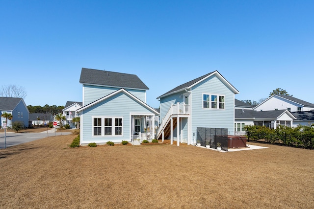 rear view of property with a lawn and a hot tub