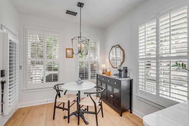 dining space featuring a notable chandelier and light wood-type flooring