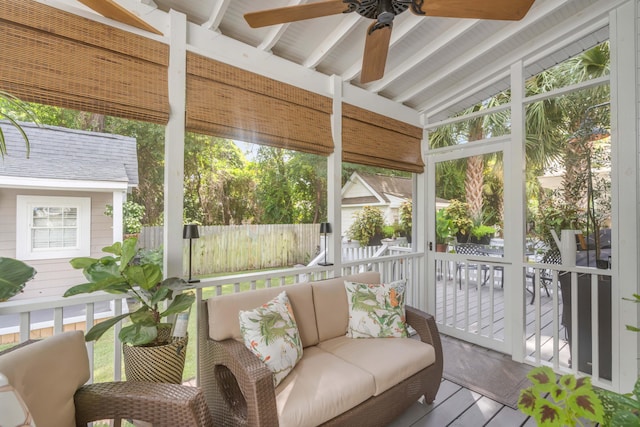 sunroom / solarium featuring ceiling fan, plenty of natural light, and lofted ceiling with beams