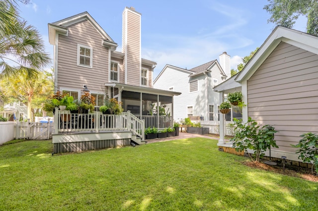 rear view of house with a sunroom, a deck, and a lawn