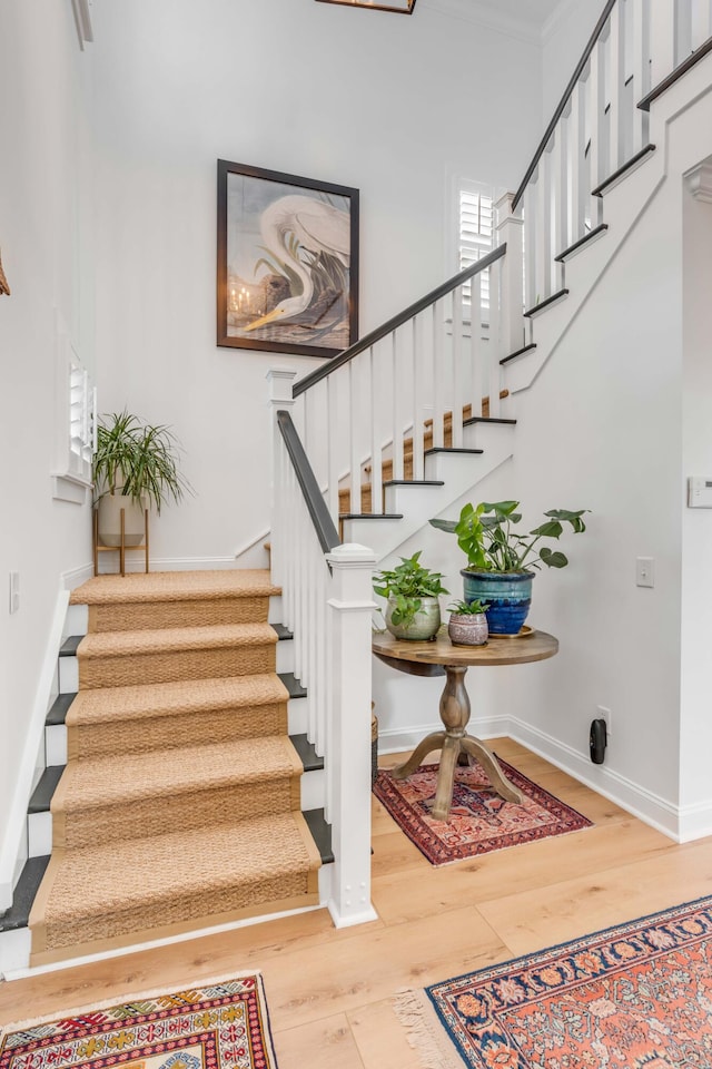 stairway with hardwood / wood-style flooring and crown molding