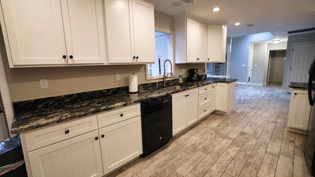 kitchen with white cabinetry, light hardwood / wood-style flooring, dishwasher, dark stone countertops, and sink