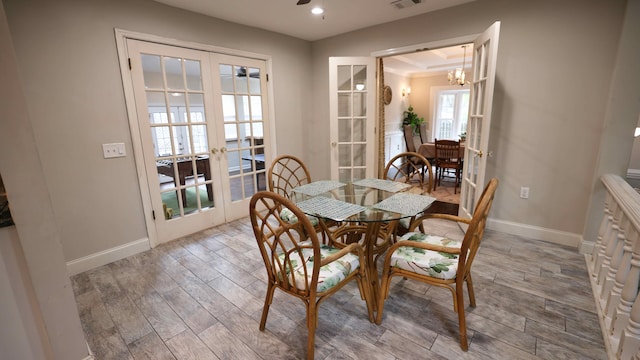 dining area with french doors, crown molding, hardwood / wood-style flooring, and a chandelier