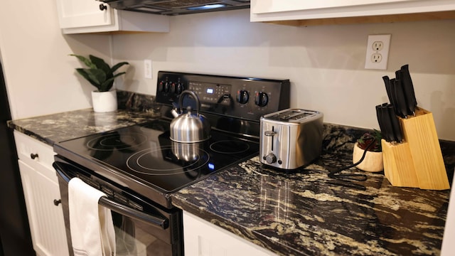 kitchen featuring black range with electric stovetop, white cabinetry, and dark stone countertops