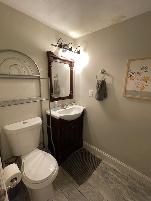 bathroom with vanity, toilet, and hardwood / wood-style flooring