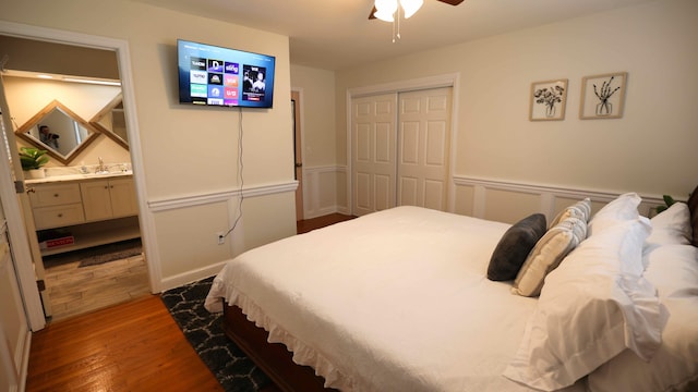 bedroom with ceiling fan, dark wood-type flooring, a closet, ensuite bath, and sink