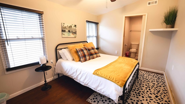 bedroom with multiple windows, hardwood / wood-style flooring, ensuite bath, and vaulted ceiling