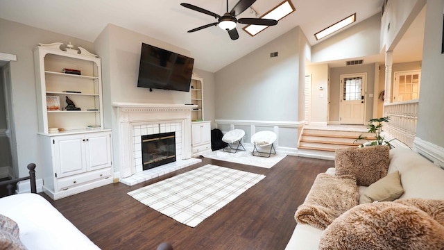 living room with ceiling fan, a brick fireplace, vaulted ceiling, dark hardwood / wood-style floors, and built in shelves