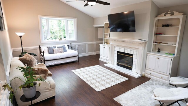 living room featuring lofted ceiling, ceiling fan, a tiled fireplace, and dark hardwood / wood-style flooring